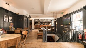 Un restaurant avec des planchers en bois, des murs en bois foncé et un coin bar équipé de tabourets et de tables.