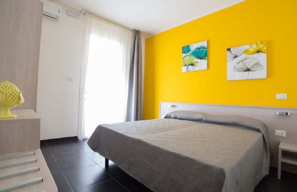 A hotel room with a bed, a small bedside table, and two wall-mounted paintings.