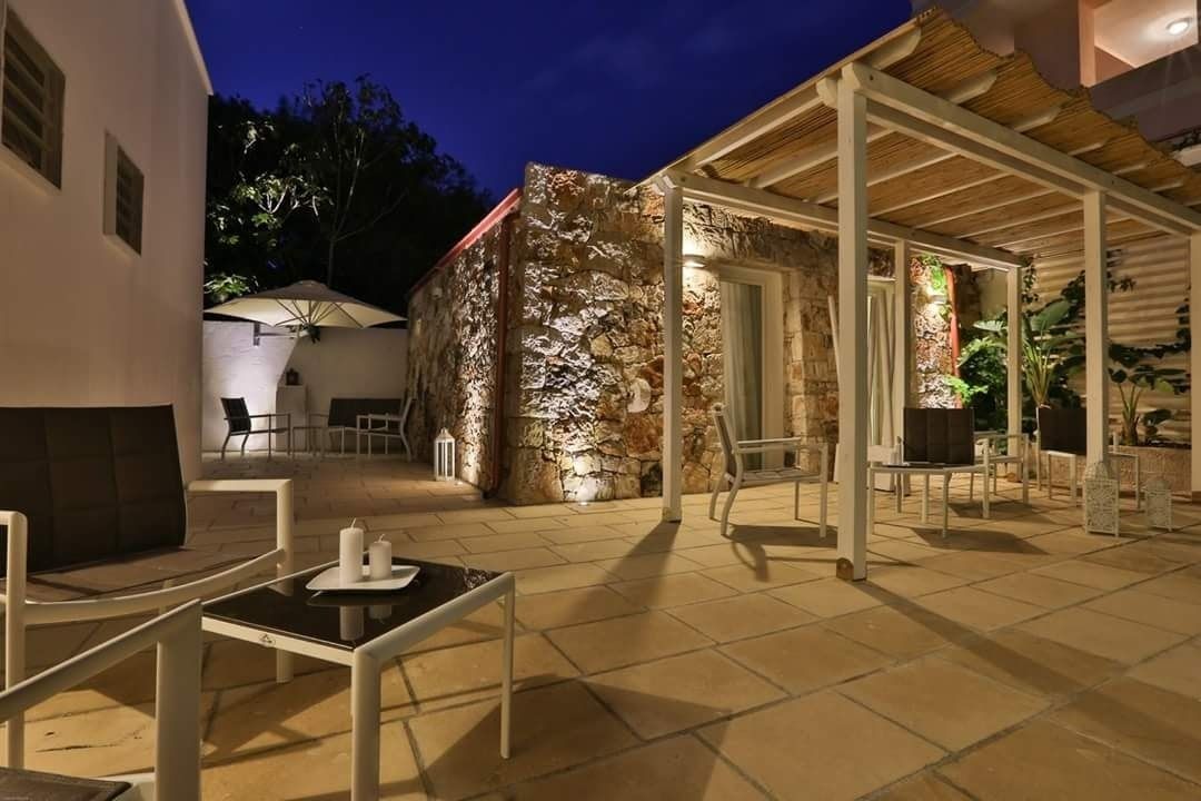 An outdoor patio area with stone walls, a covered seating area, and a table with candles.