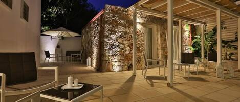 An outdoor patio area with stone walls, a covered seating area, and a table with candles.