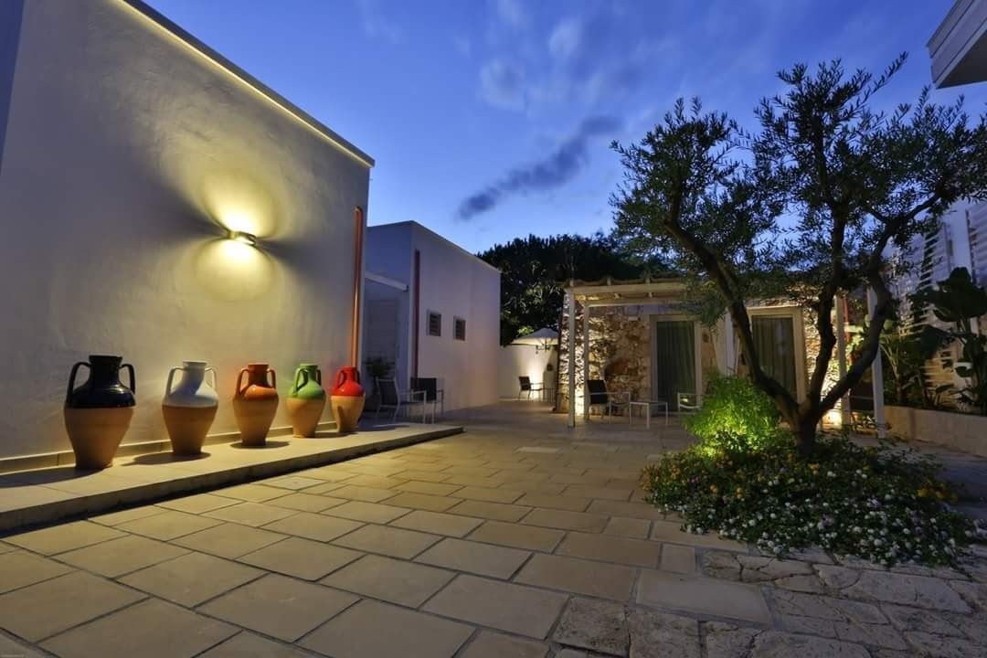 A courtyard with a row of colorful vases, a tree, and a building with a light fixture.