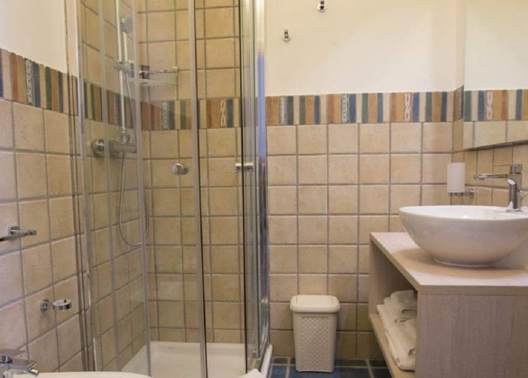 A bathroom with a glass-enclosed shower, a sink, and a toilet.