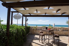 A covered outdoor seating area with a view of the sea, featuring a sign for 'la Giara Resort'. - La Giara Resort (Ugento)