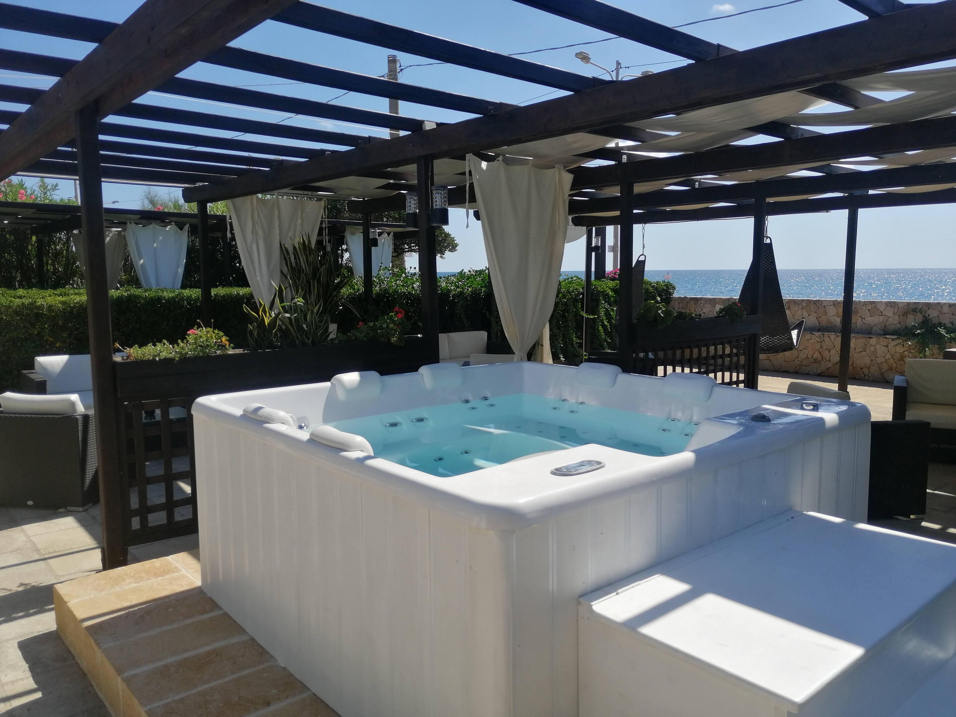A hot tub under a pergola with a view of the sea.