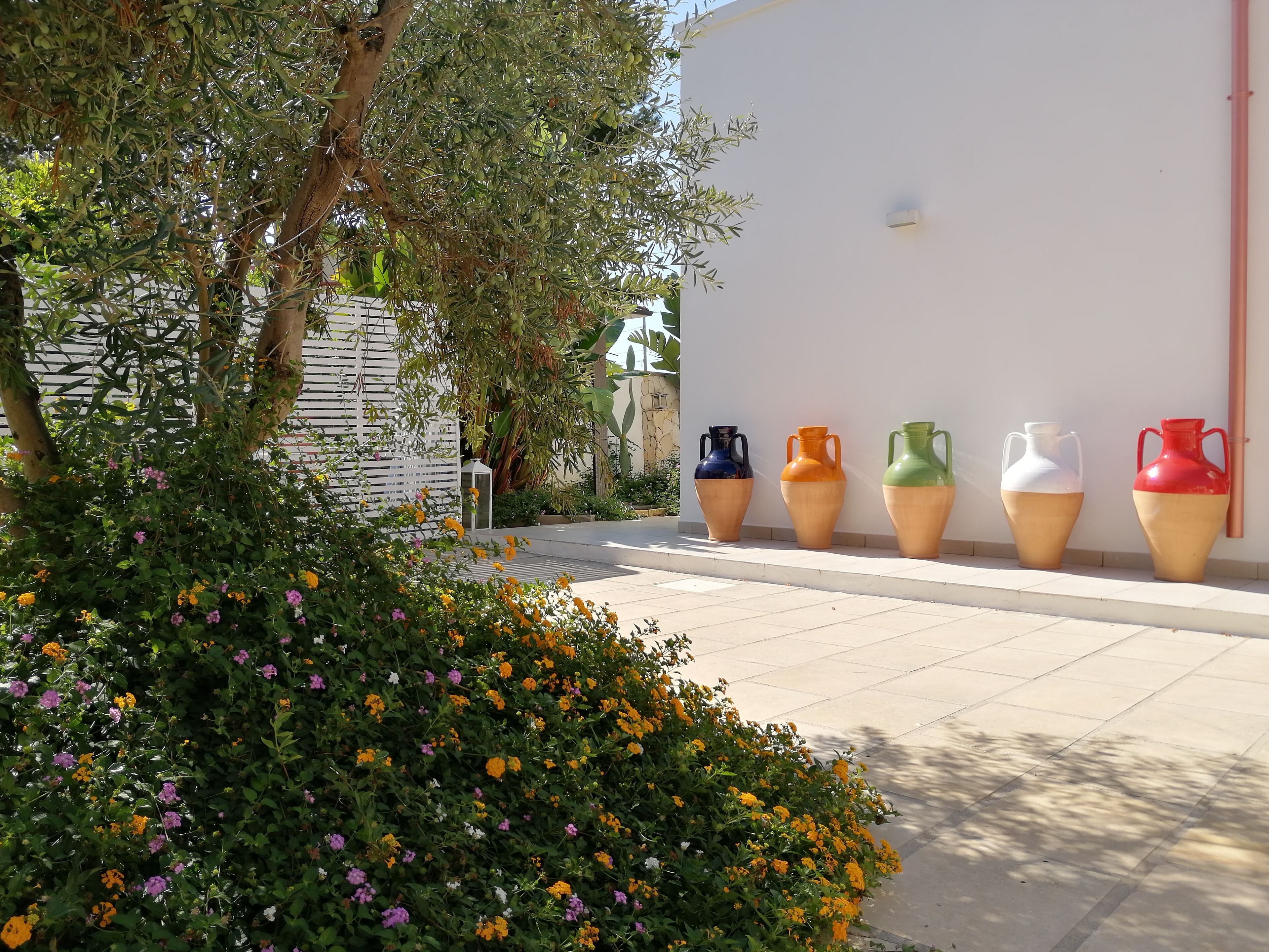 A pathway lined with colorful ceramic pots and a variety of flowering plants.