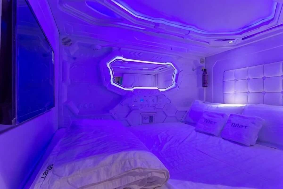 Um quarto moderno com uma cama, cabeceira e espelho fixado na parede.