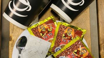 A plate with coffee cups, tea bags, and packets of instant coffee.