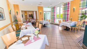 Een restaurant met verschillende tafels, stoelen en diverse tafelopstellingen.