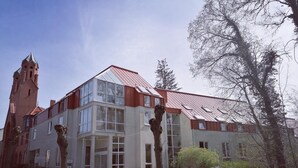 Een modern gebouw met een opvallende toren, grote ramen en een schuin dak.