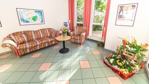 Een woonkamer met een gestreepte bank, een klein rond tafeltje en een bloemstuk.