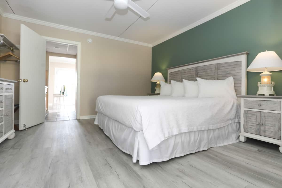 A bedroom with a large bed, two bedside lamps, a wooden headboard, and a white dresser.