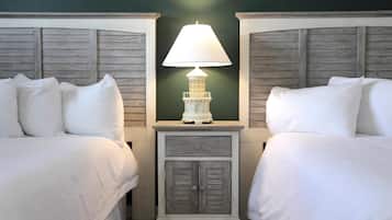 A room with two beds, a nightstand with a lamp, and a small cabinet.
