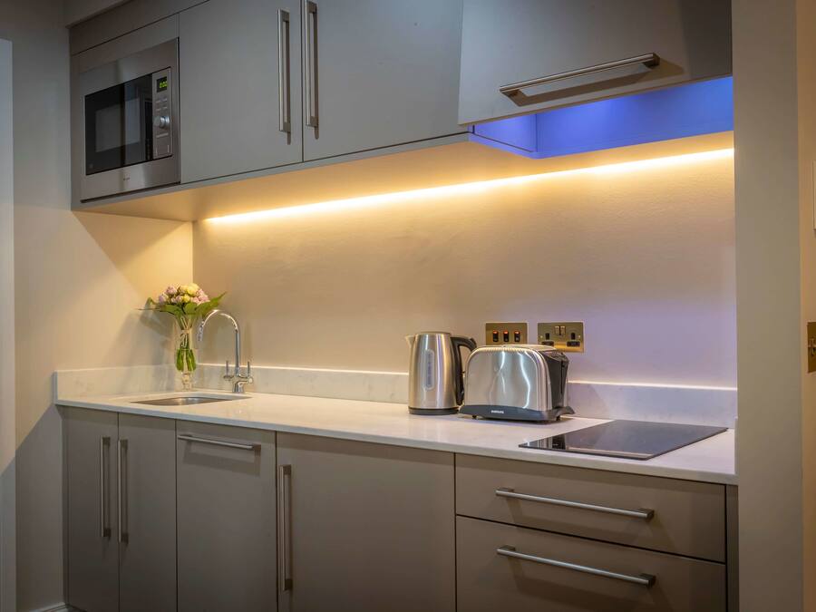 A modern kitchen with a built-in microwave, stainless steel appliances, and under-cabinet lighting.