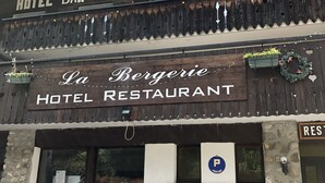 En hotelbar og restaurant med et rustikt udseende, træfacade og et skilt, der angiver, at det er et 2-stjernet etablissement.