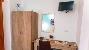 Ett litet rum med ett skrivbord i trä, en spegel, en tv och en garderob.