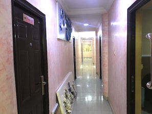 Un pasillo de hotel con un letrero para la habitación 101, piso de baldosas y una puerta a la izquierda.