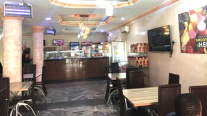 A restaurant interior with marble flooring, a counter with Pepsi and Coca-Cola refrigerators, and a menu board. - Sweet Savor Hotels & Suites (Lagos)