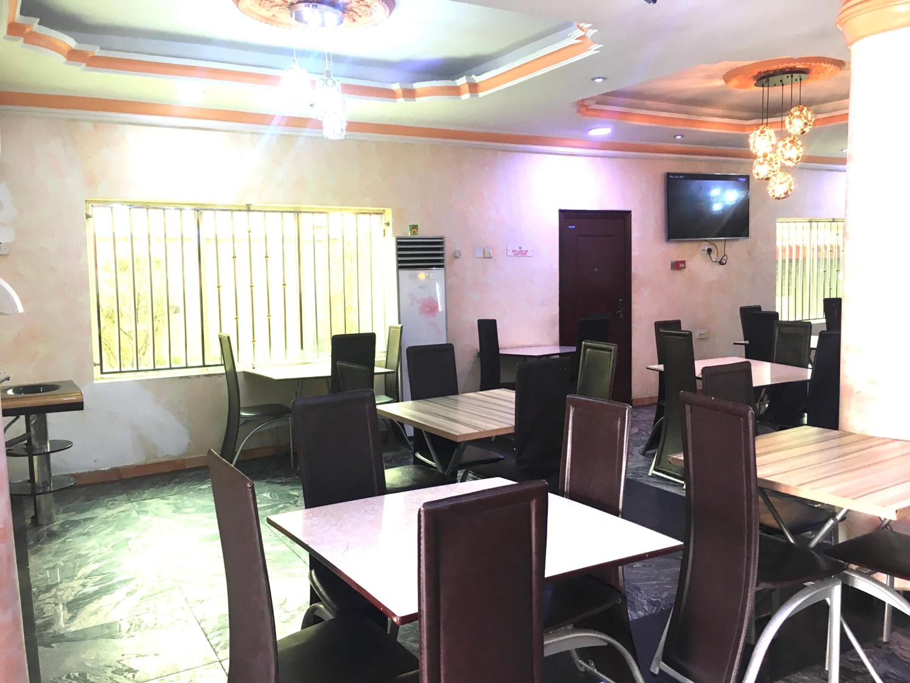A conference room with multiple tables and chairs, a television mounted on the wall, and a window with bars.