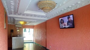 A hotel lobby with a marble floor, a reception desk, and a television screen displaying a program. - Sylvia's Place (Ibadan)