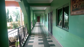 A corridor with green walls and a checkered floor, leading to a door at the end. - Sylvia's Place (Ibadan)