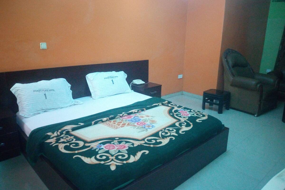 A bedroom with a bed, a nightstand, a chair, and a small table.