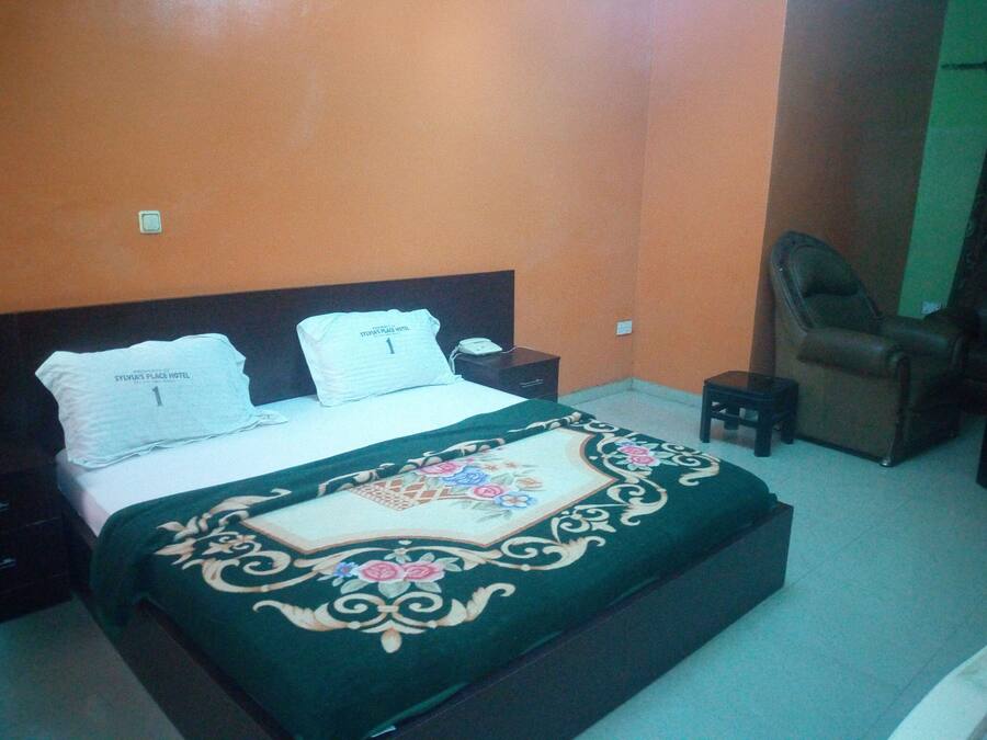 A bedroom with a bed, a nightstand, a chair, and a small table.