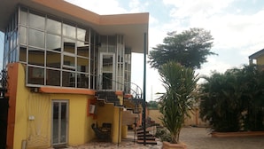 A building with a yellow facade, large windows, and a staircase leading to an upper level. - Sylvia's Place (Ibadan)