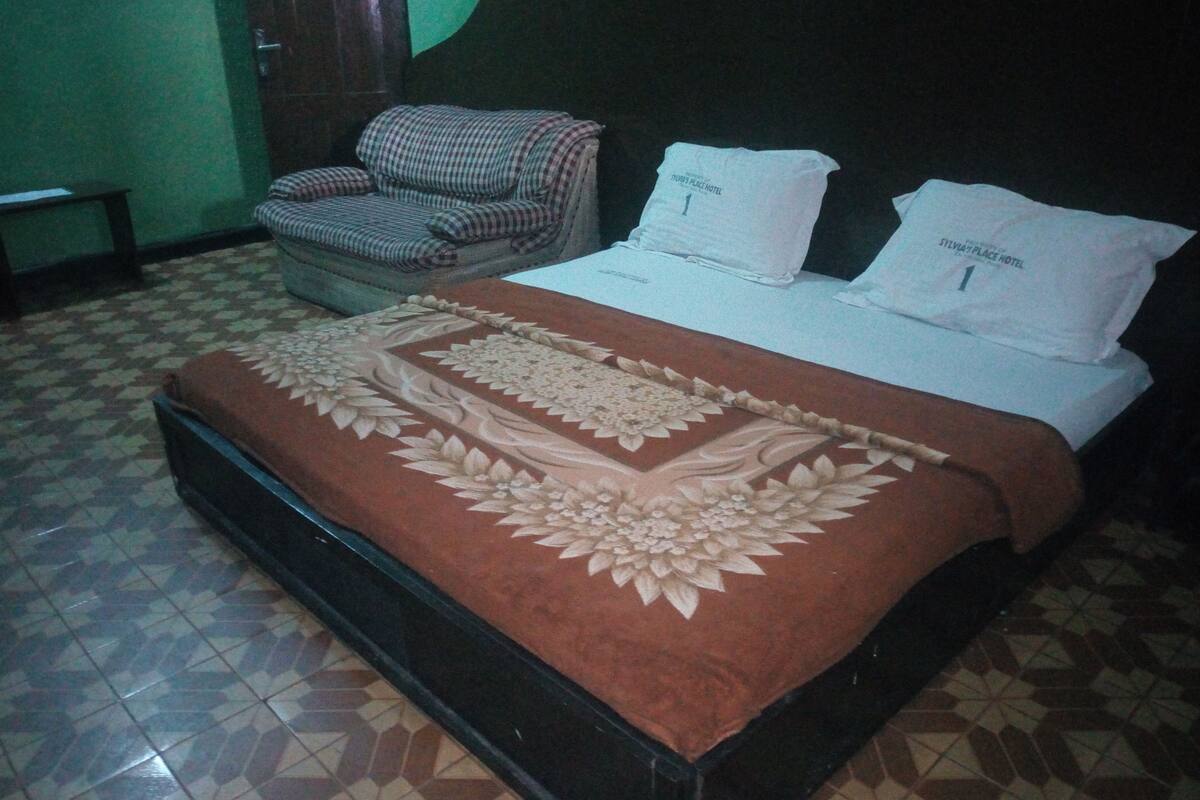 A hotel room with a bed, a chair, and a small table.
