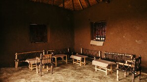 A rustic room with wooden benches and tables, a thatched roof, and a simple, unadorned wall. - Degosach Eco Lodge (Lalibela)