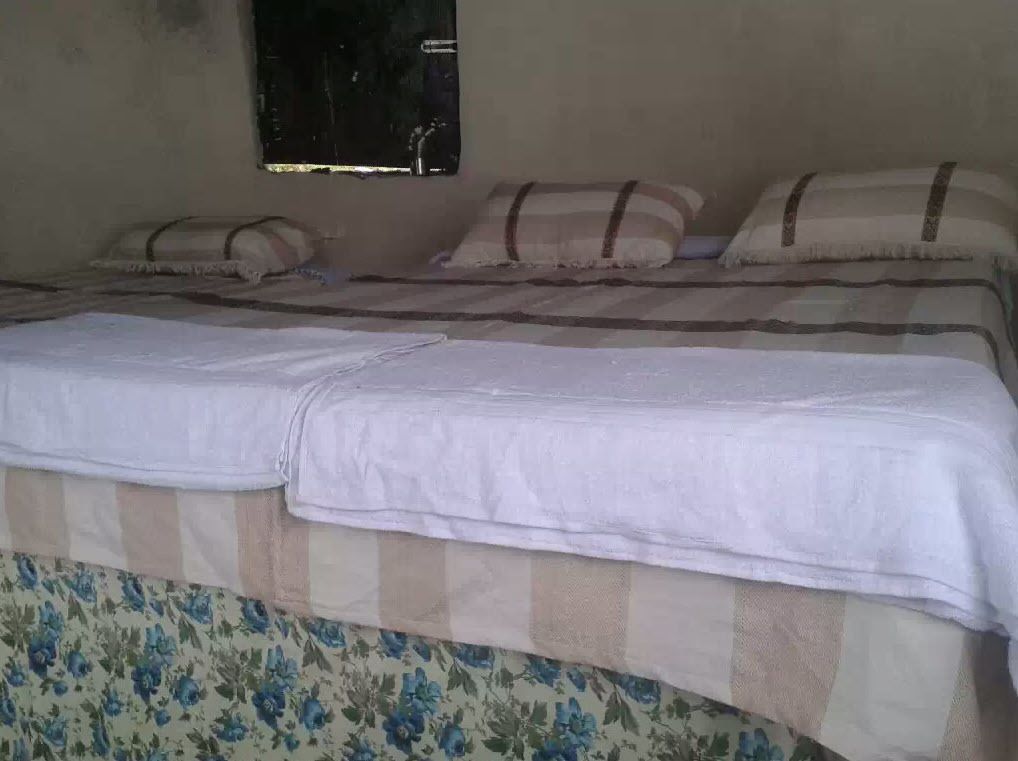 Un lit recouvert d’une couvre-lit à motifs floraux et d’un simple drap blanc.
