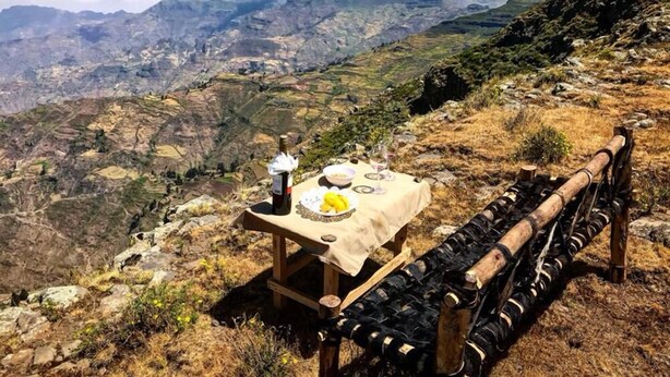 A picnic setup with a table and wine bottles on a mountain trail. - Degosach Eco Lodge (Lalibela)