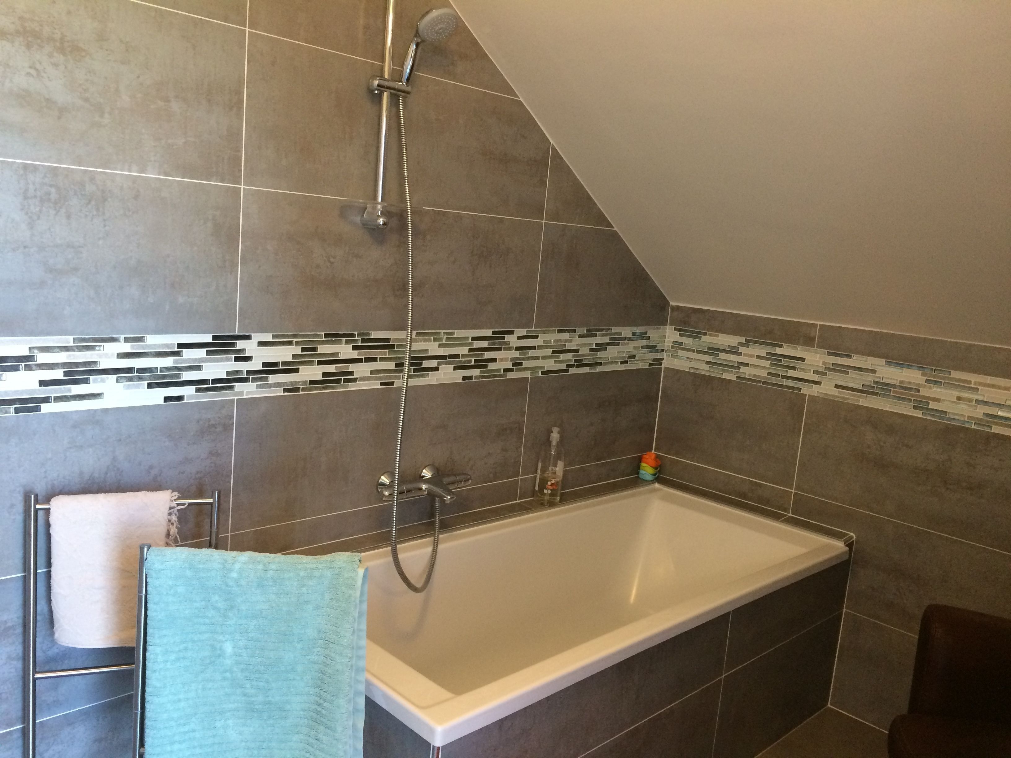 A bathroom with a bathtub, shower, and tiled walls.