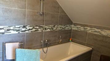 A bathroom with a bathtub, shower, and tiled walls.