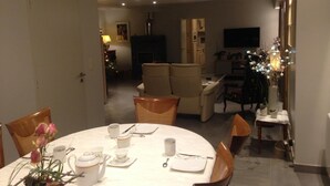 Un coin repas avec une table ronde dressée pour quatre personnes, des chaises et un vase rempli de fleurs.