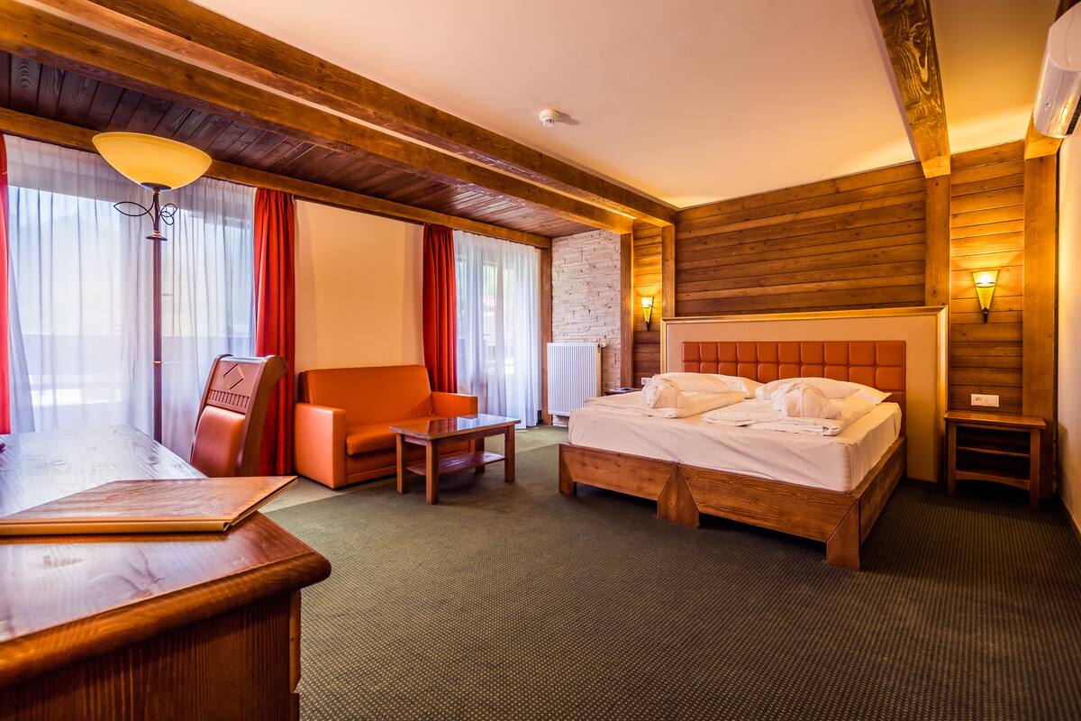 Una habitación de hotel con una cama de madera, un escritorio, una silla y una mesita.