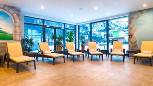 A waiting area with wicker chairs and a mural on the wall. - Hotel Victoria Kaprun (Kaprun)