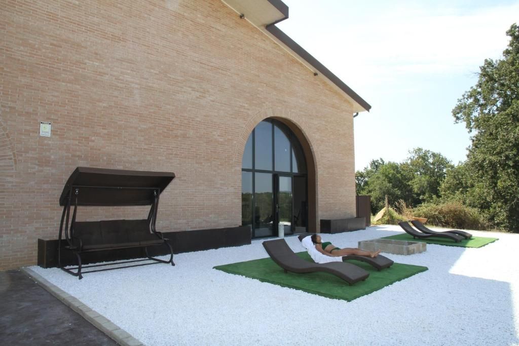 Un edificio con facciata in mattoni, un'ampia porta ad arco e una zona patio con poltrone relax e un'amaca.