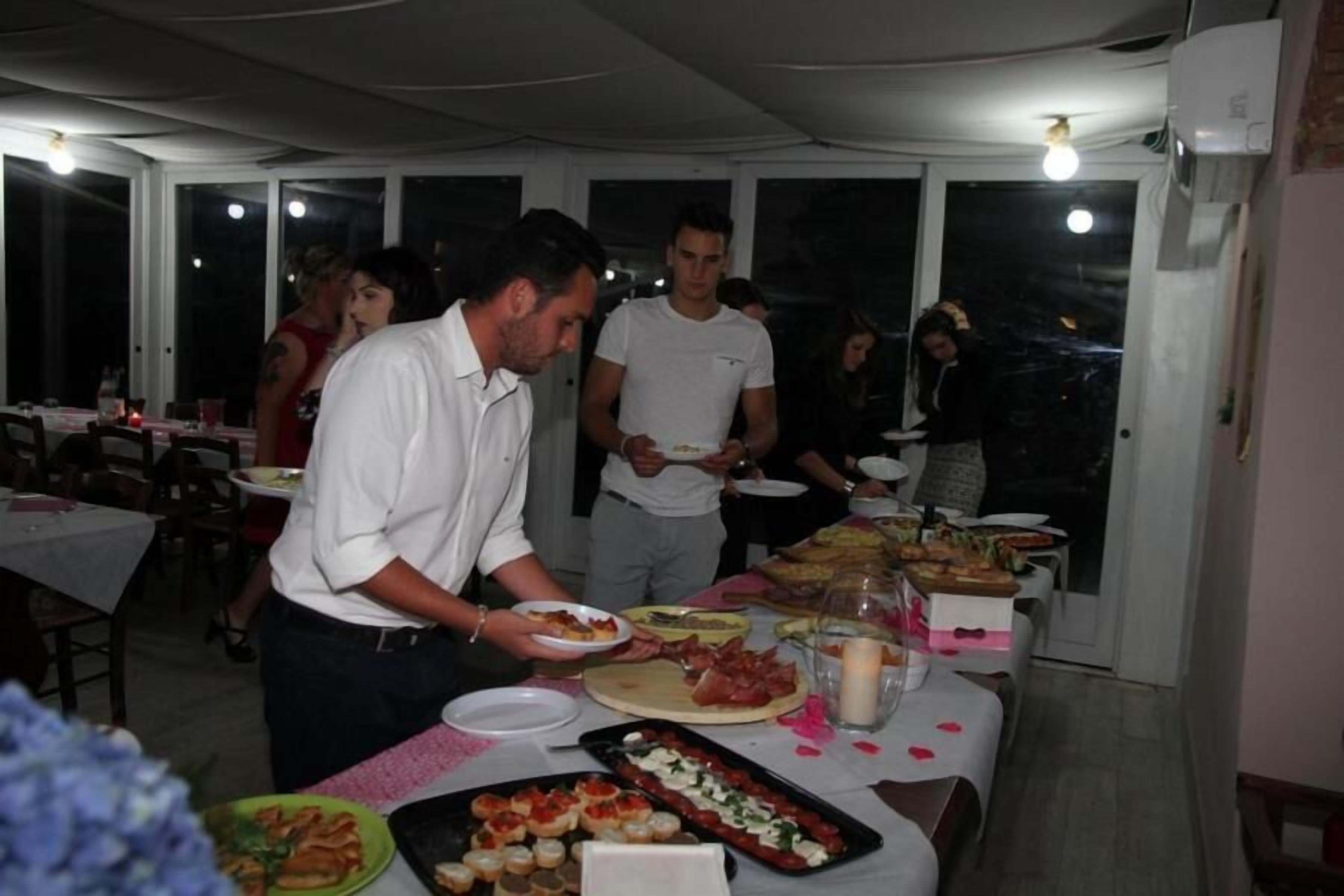 Ein Essbereich mit gedeckten Tischen, ein Buffet mit verschiedenen Speisen und eine Person, die Essen serviert.