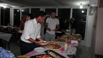 Ein Essbereich mit gedeckten Tischen, ein Buffet mit verschiedenen Speisen und eine Person, die Essen serviert.
