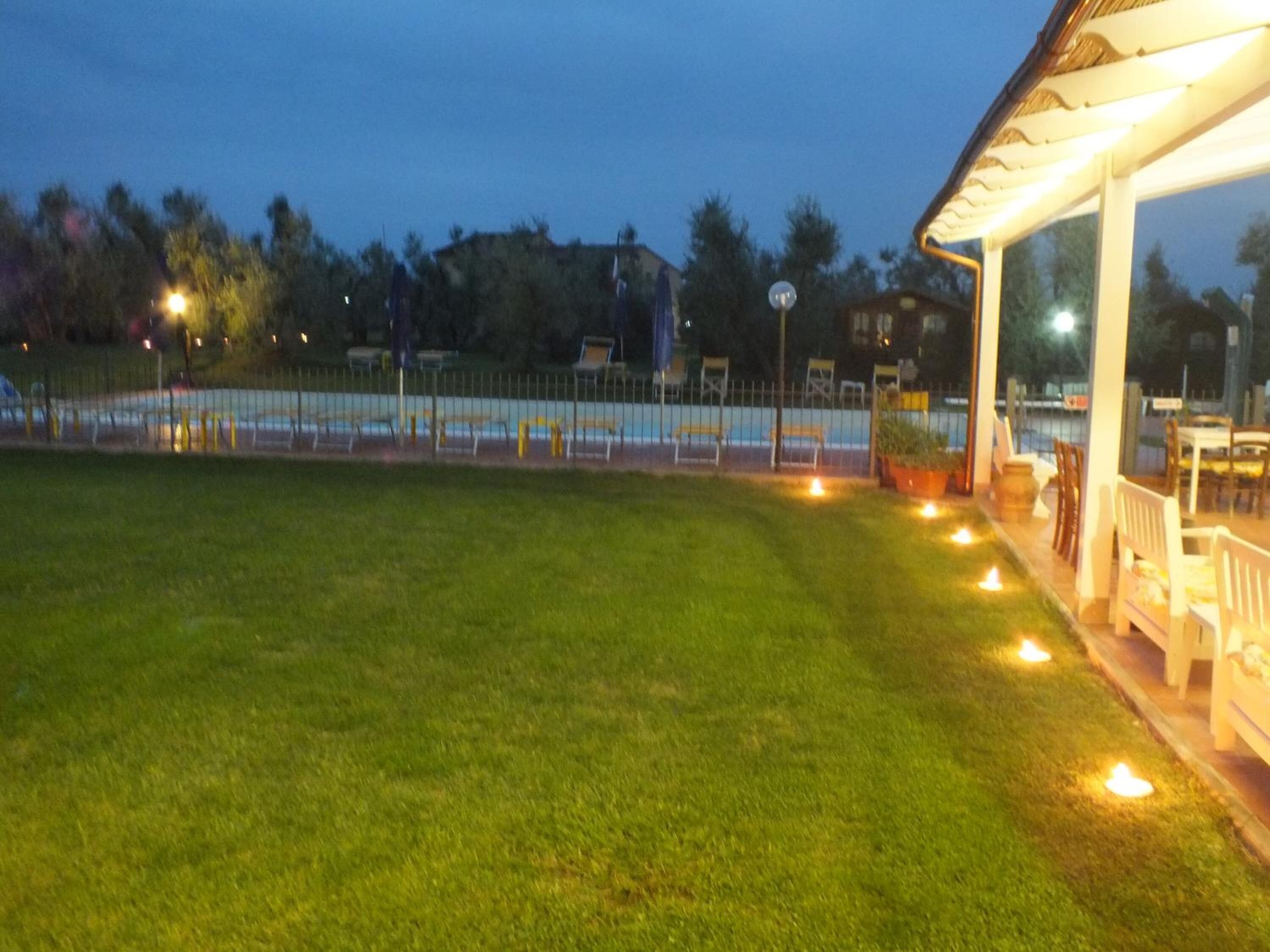 Un'area verde curata con un'area salotto coperta e una piscina sullo sfondo.