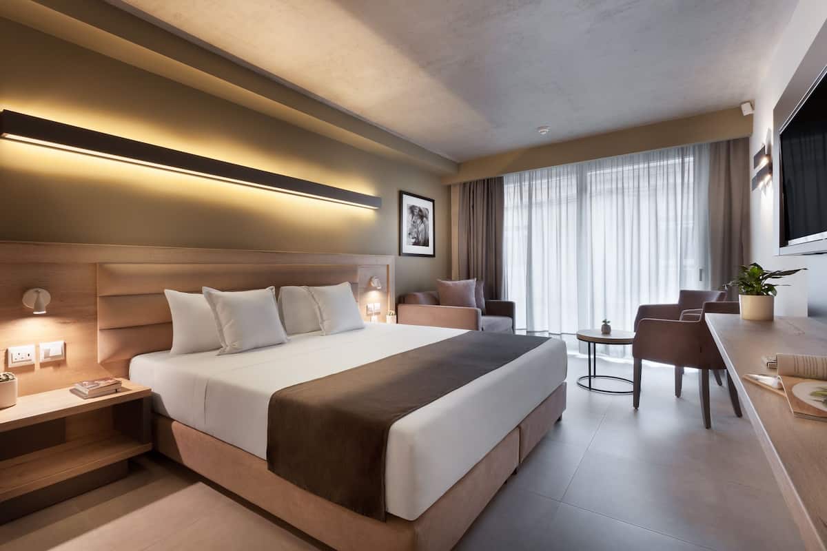 A modern hotel room with a large bed, bedside tables, a desk, and a chair.