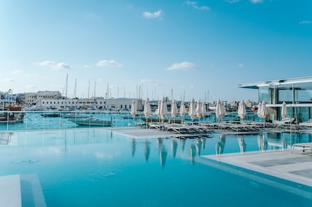 Una piscina al aire libre, sombrillas, sillones reclinables de piscina