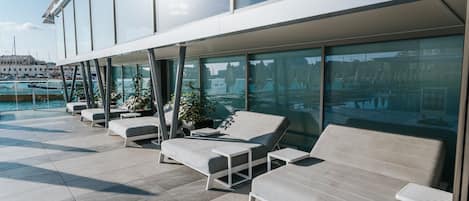 Eine moderne Lounge im Freien mit verschiedenen Sitzgelegenheiten und Blick auf den Hafen.