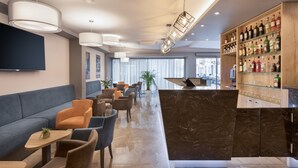 A modern bar area with seating, a television, and a variety of liquor bottles. - Azur Hotel by ST Hotels (Gzira)