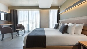 A modern hotel room with a large bed, a desk, and a chair. - Azur Hotel by ST Hotels (Gzira)