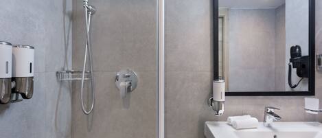 Un baño moderno con ducha, lavabo, espejo y secador de pelo.