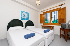 A hotel room with two beds, a small table, a television, and a window with wooden shutters. - Laurel 8 pax - Javea, Costa Blanca (Javea)