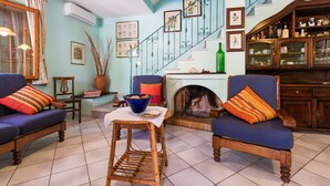 A living room with two blue armchairs, a wooden coffee table, a fireplace, and a staircase with decorative railings. - Calagonone Villa with garden bbq, WiFi / AC --- IUN Code: P2169 (Dorgali)