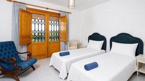 Een hotelkamer met twee bedden, een stoel en een raam met gordijnen.