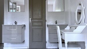 Een badkamer met twee wastafels, een spiegel en een deur.